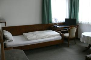 a bedroom with a bed and a desk with a computer at Hotel zur Germania in Ostfildern