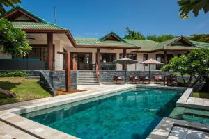 a swimming pool in front of a house at Idyllic Samui Beach Villa Resort in Choeng Mon Beach