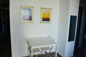 una mesa blanca contra una pared blanca con dos cuadros en Beach apartment Villajoyosa, en Villajoyosa