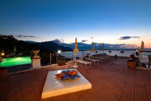 a deck with chairs and a swimming pool at dusk at Villa Gioiello in Amalfi