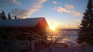 un edificio con el sol saliendo por encima de la nieve en Hotel Garni Gästehaus Karin, en Sankt Stefan im Lavanttal