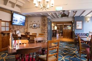 een eetkamer met een tafel en stoelen en een televisie bij The Swan by Innkeeper's Collection in Coleshill