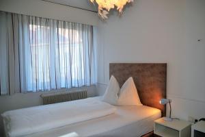 a bedroom with a white bed with a large window at Hotel Hecher in Wolfsberg