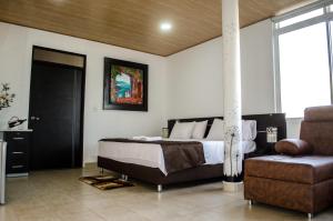 a bedroom with a bed and a couch and a chair at Hotel Quinta del Sol in Arauca