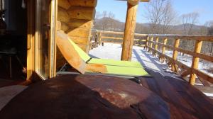 uma cadeira de baloiço no alpendre de uma cabana de madeira em CzapaDziada em Zatwarnica