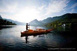 Un homme est debout sur un bateau sur un lac dans l'établissement Happy Stay Apartment, à Bad Mitterndorf