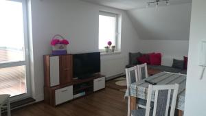 uma sala de estar com uma televisão e uma mesa e cadeiras em apartman Lusy em Veľká Lomnica