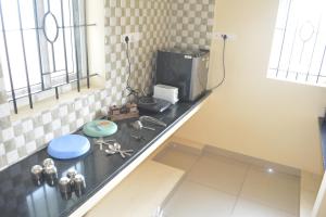 una cocina con encimera y TV. en JP Nivaas Guest House, en Mayiladuthurai