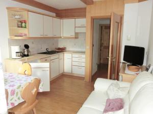 una pequeña cocina con armarios blancos y un sofá blanco en Apartments Sotbosch, en La Villa