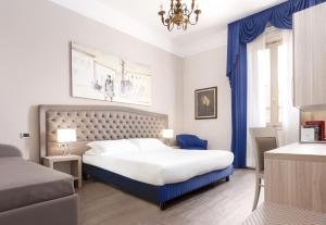 una camera da letto con un grande letto con tende blu e un lampadario a braccio di Hotel Ristorante Ala d'Oro a Lugo