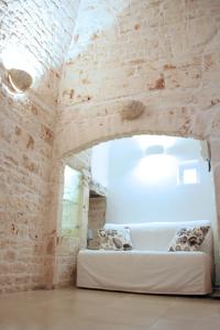 トゥーリにあるDimora Morelloの白いソファが備わるレンガの壁の客室です。