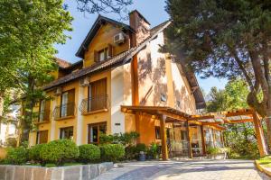 una casa amarilla con un camino delante de ella en Pousada Águia Branca, en Gramado