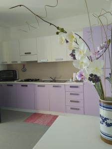 トルトリにあるAppartamenti Demurtasの白いキャビネットと花瓶付きのキッチン
