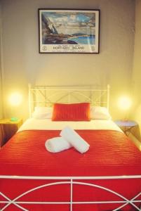 Una cama roja y blanca con dos toallas. en Vagabonds Hostel, en Belfast