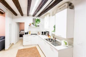 a kitchen with white cabinets and a wooden ceiling at Cà Biennale: scoprire gli angoli nascosti! in Venice