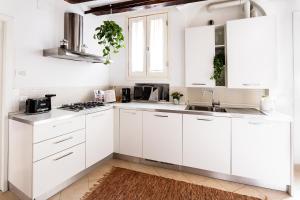 a white kitchen with white cabinets and a sink at Cà Biennale, scoprire la Venezia nascosta! in Venice