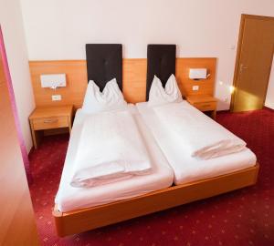 2 Betten in einem Hotelzimmer mit weißer Bettwäsche in der Unterkunft Gasthaus Abram in Auer