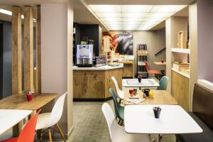 a restaurant with tables and chairs and a kitchen at ibis Clichy Centre Mairie in Clichy