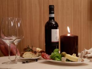 butelkę wina, talerz jedzenia i świecę w obiekcie Locanda Black and White Sondrio w mieście Sondrio +24 zdjęcia