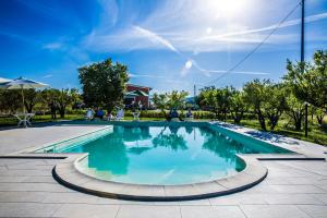 a swimming pool with blue water in a park at Agriturismo Aurea in Torretta