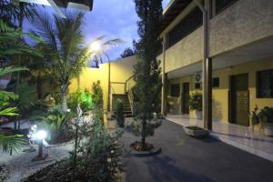 a courtyard of a building with palm trees and lights at Pousada Rozam in Olímpia