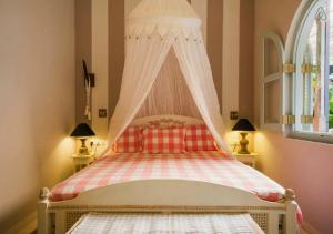1 dormitorio con 1 cama con dosel y 2 lámparas en LE JARDIN DU FORT - GALLE, en Galle