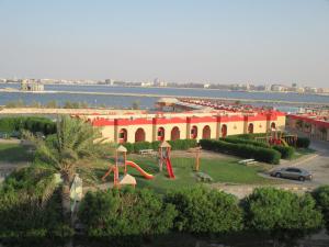 ein großes Gebäude mit einem Spielplatz vor dem Wasser in der Unterkunft Sea Club Resort in Dammam
