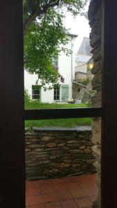 una ventana con vistas a una pared de piedra y a una casa blanca en Le Clos De La Bouteille en Angers