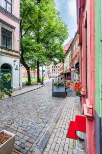Una calle adoquinada en una ciudad con un banco rojo en Dome square apartment, Old Town, en Riga 8 fotos más