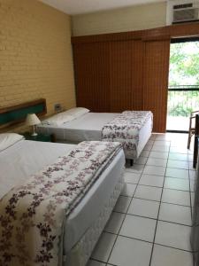 a hotel room with two beds and a window at Flat Angra Portogalo in Angra dos Reis