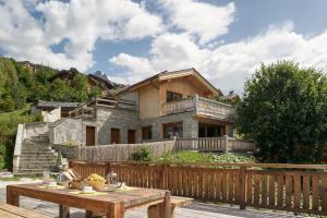 a house with a wooden fence and a wooden table at Chalet Zebra in Méribel