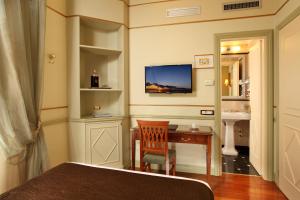 a bedroom with a bed, desk, chair and a television at Hotel Degli Aranci in Rome