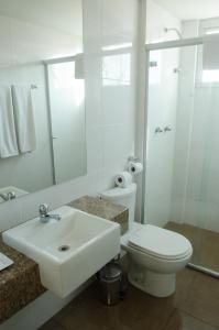 uma casa de banho branca com um lavatório e um WC em Ímpar Suítes Expominas em Belo Horizonte