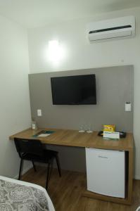Uma TV ou centro de entretenimento em Ímpar Suítes Expominas