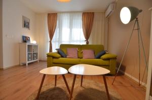 ein Wohnzimmer mit einem grünen Sofa und einem Tisch in der Unterkunft AVA Apartments ADORA FOREST 1 in Timişoara