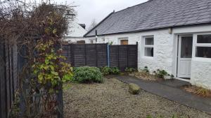 a white house with a black fence and a yard at Silver Ridge, 2 House O` Hill in Newton Stewart