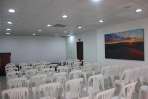 a conference room with white chairs and a large screen at Hotel Médano in Trujillo