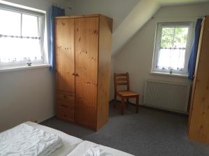 a bedroom with a wooden cabinet and a chair at Ferienhaus Zinnowitz in Zinnowitz