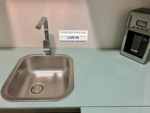 a sink in a kitchen with a sign on the wall at LIVE-IN Wertheim am Main in Wertheim