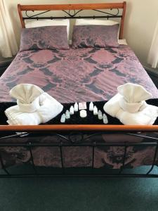 a bed with a wooden frame with two towels on it at The Kentish Hotel in Waiuku