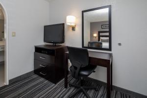Zimmer mit einem Schreibtisch, einem TV und einem Spiegel in der Unterkunft Redwood Creek Inn in Redwood City