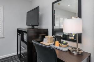 a room with a desk with a television and a lamp at Redwood Creek Inn in Redwood City