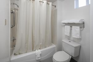 a white bathroom with a shower curtain and a toilet at Redwood Creek Inn in Redwood City +5 photos