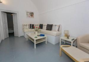 una sala de estar blanca con sofás y mesas. en Santoimage house en Oia