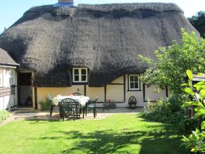 a house with a thatched roof with a table and chairs at The Stable in Eastleigh