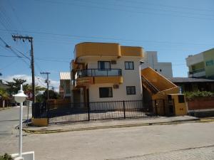 a yellow and white building with a fence around it at Residencial Sol Nascente in Bombinhas