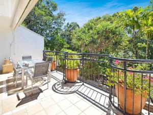 balcón con mesa, sillas y árboles en Bayona Apartments, en Noosa Heads