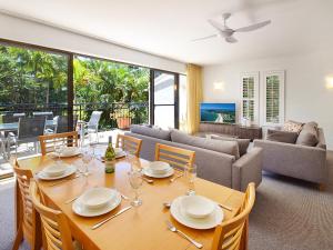 a dining room with a table and a couch at Bayona Apartments in Noosa Heads