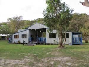 a white building with a tree in the yard at Orchid Beach Retreat Orchid Beach Fraser Island in K'gari Island (Fraser Island)