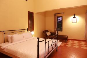 a bedroom with a bed and a chair at Villa Di Montagna at Khaoyai in Pak Chong